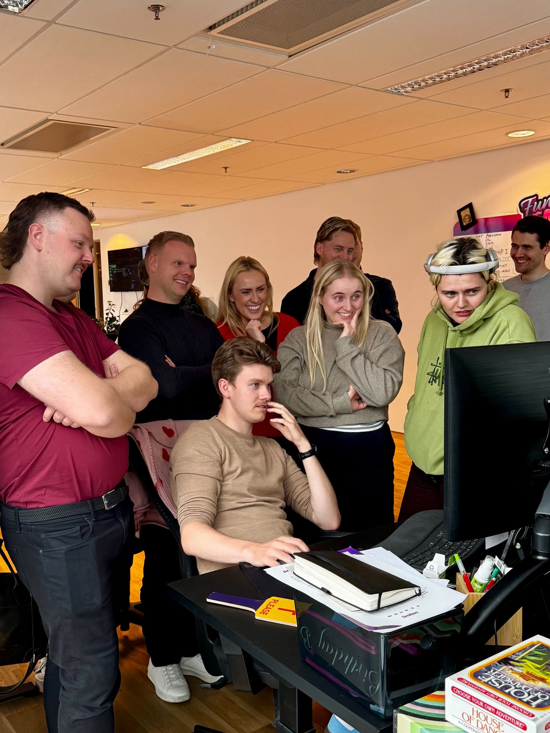 The team crowded around one desk monitor, watching over a colleague’s shoulder